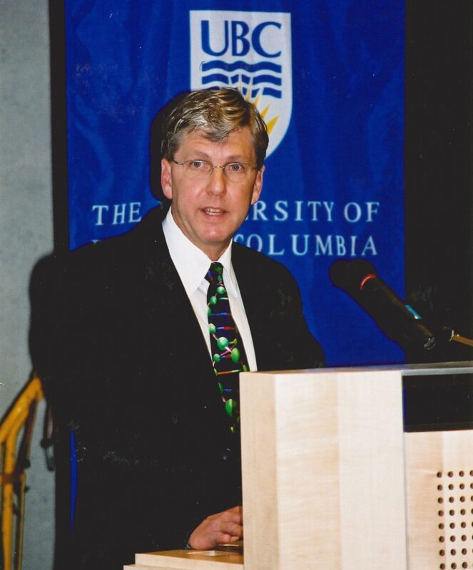 Dr. Phil Hieter stands behind a podium in the MSL seminar room, delivering a speech for the opening of the building.